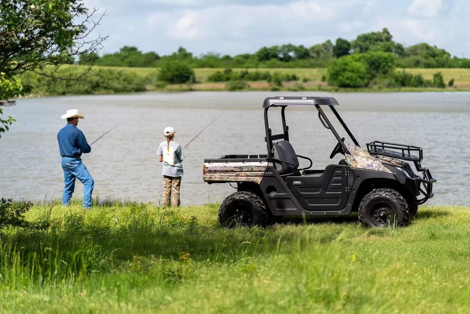 Two people fishing by a lake next to a parked UTV, representing a silent utility vehicle and electric UTV for farm and outdoor recreation.