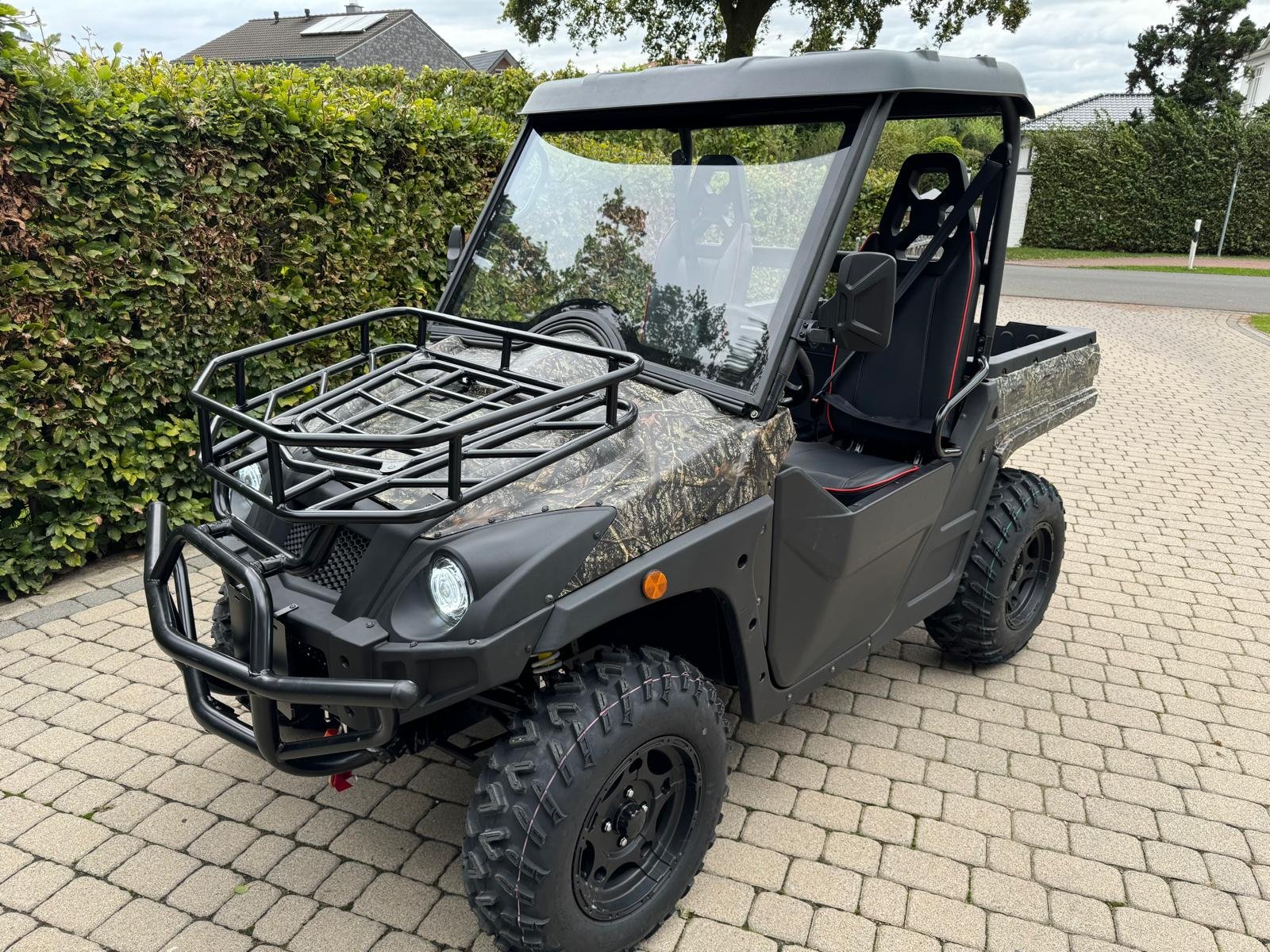 An electric UTV with Dual A-Arm independent suspension parked on a paved driveway, showcasing its rugged off-road chassis architecture.