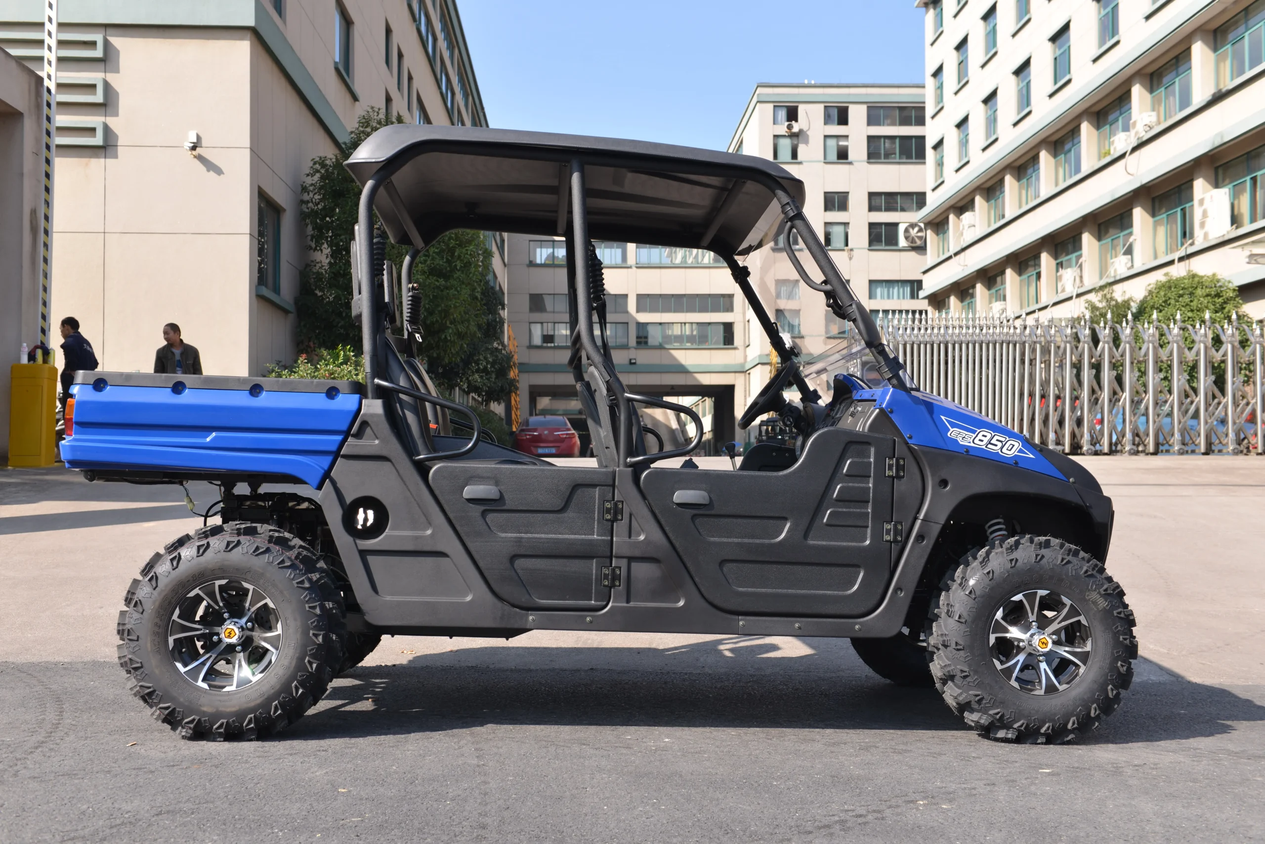 Side view of a blue crossover UTV with a heavy-duty cargo bed and spacious seating