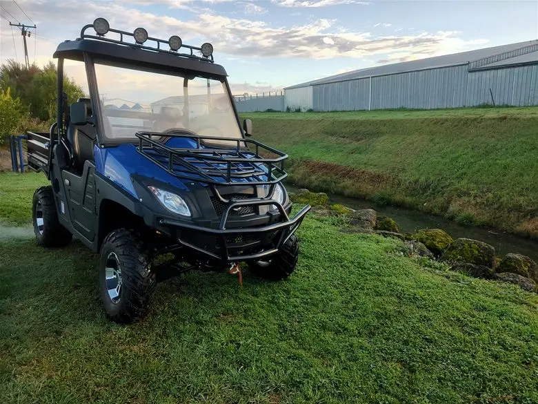 Off-road electric utility vehicle navigating uneven grass terrain and steep slopes