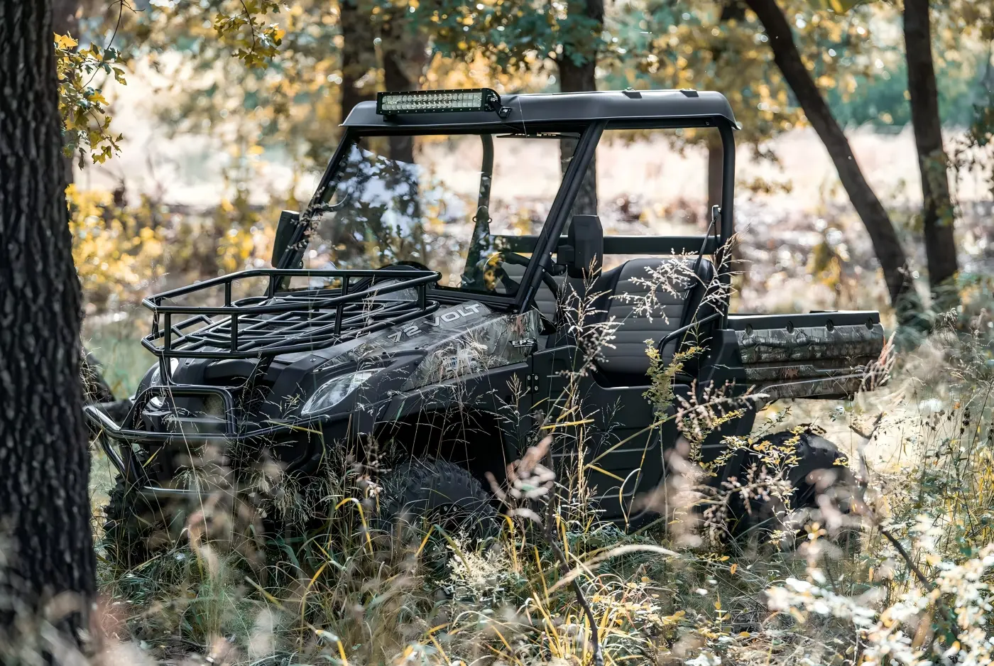 Camouflaged gasoline UTV parked in a woodland trail environment for farm work and off-road riding