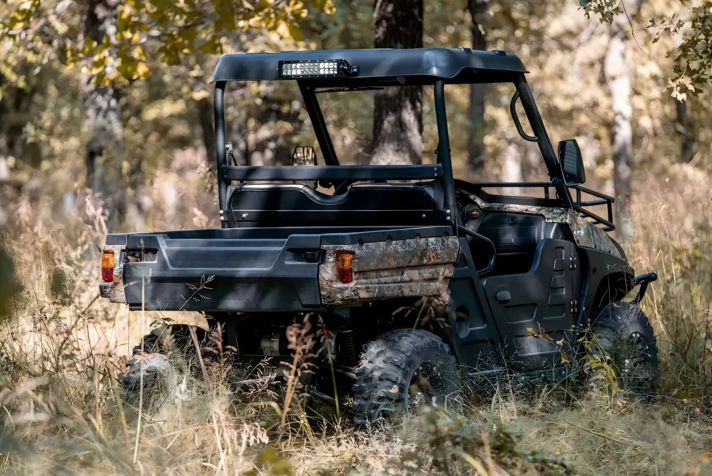 Rear view of a camouflaged gasoline UTV highlighting its cargo box for farm work and trail transportation