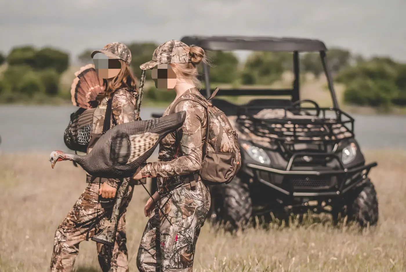 Operators carrying equipment near a commercial gasoline UTV during outdoor farm and ranch operations