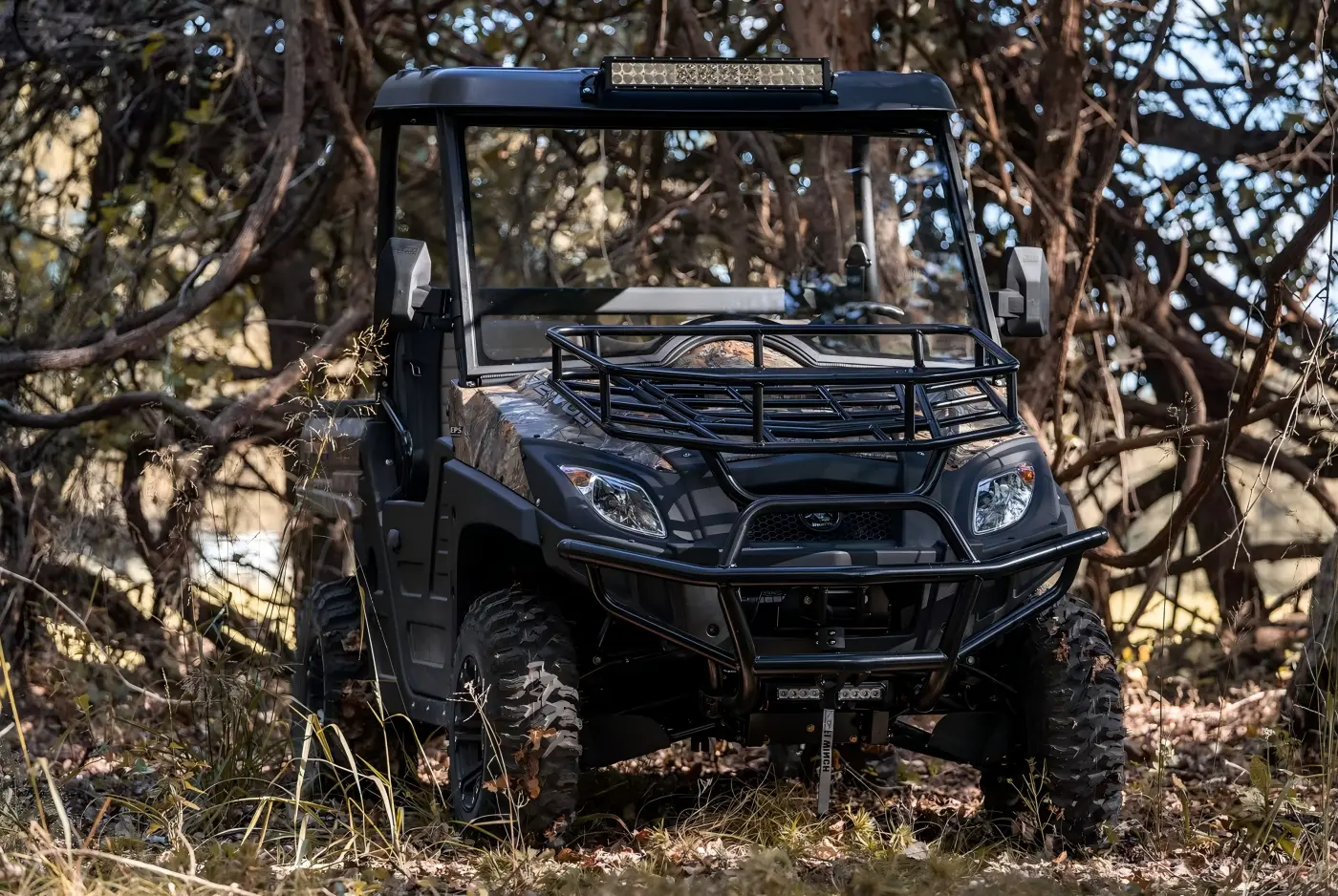 Custom fuel UTV parked in a rugged woodland environment for all-terrain utility tasks
