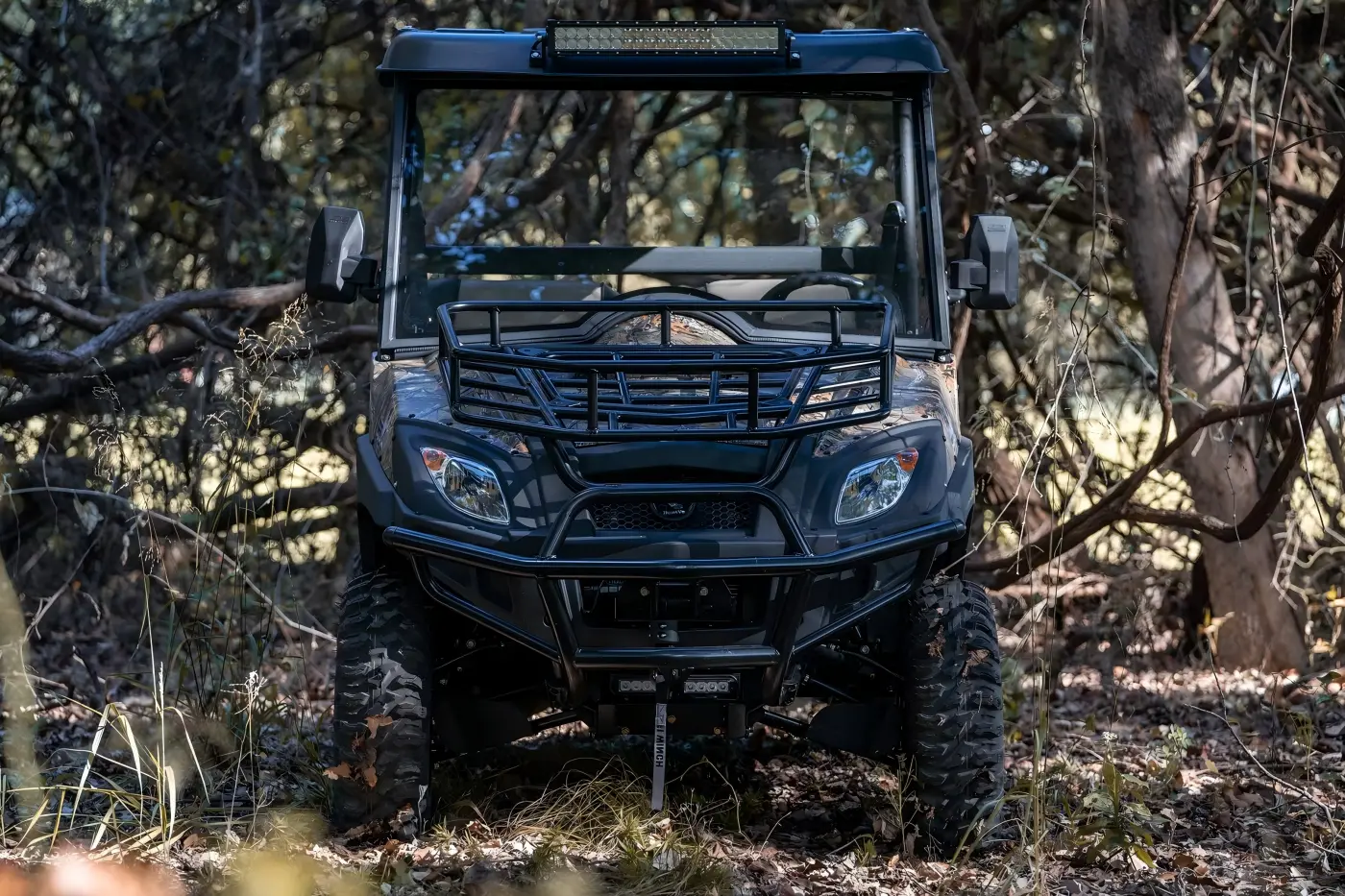 Custom fuel UTV front view parked in a rugged woodland environment for all-terrain exploration