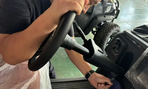 Technician assembling and testing the steering system of a Greatwork electric golf cart.