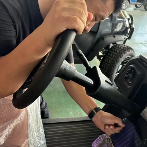 Technician assembling and testing the steering system of a Greatwork electric golf cart.