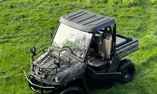 An electric UTV driving on a green pasture, demonstrating zero-emission operations in ecologically sensitive zones.