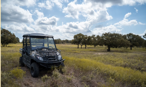 Off-road utility vehicle with Dual A-Arm independent suspension driving on agricultural grassland.
