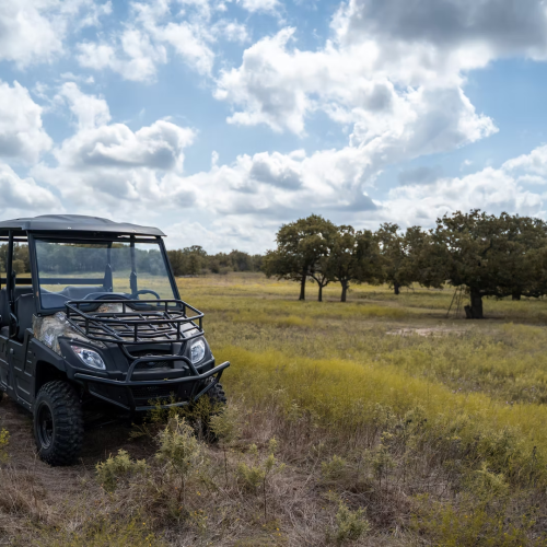 Off-road utility vehicle with Dual A-Arm independent suspension driving on agricultural grassland.